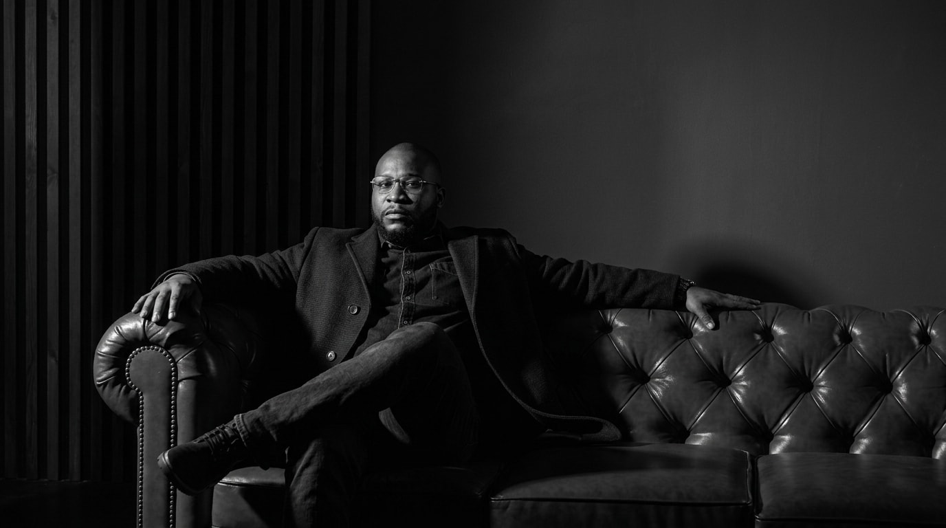 Itse Sagay seated on a leather sofa, black and white